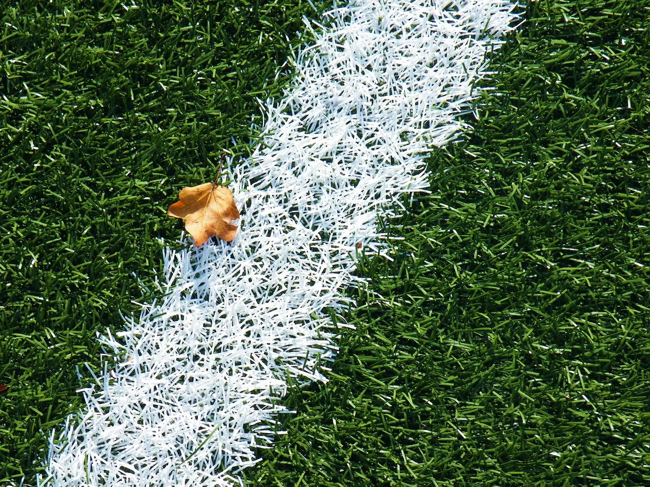 A professional football stadium pitch during an evening match under stadium lights.