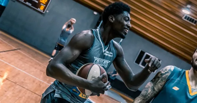 Engaging moment of basketball players during an indoor training session on a wooden court.