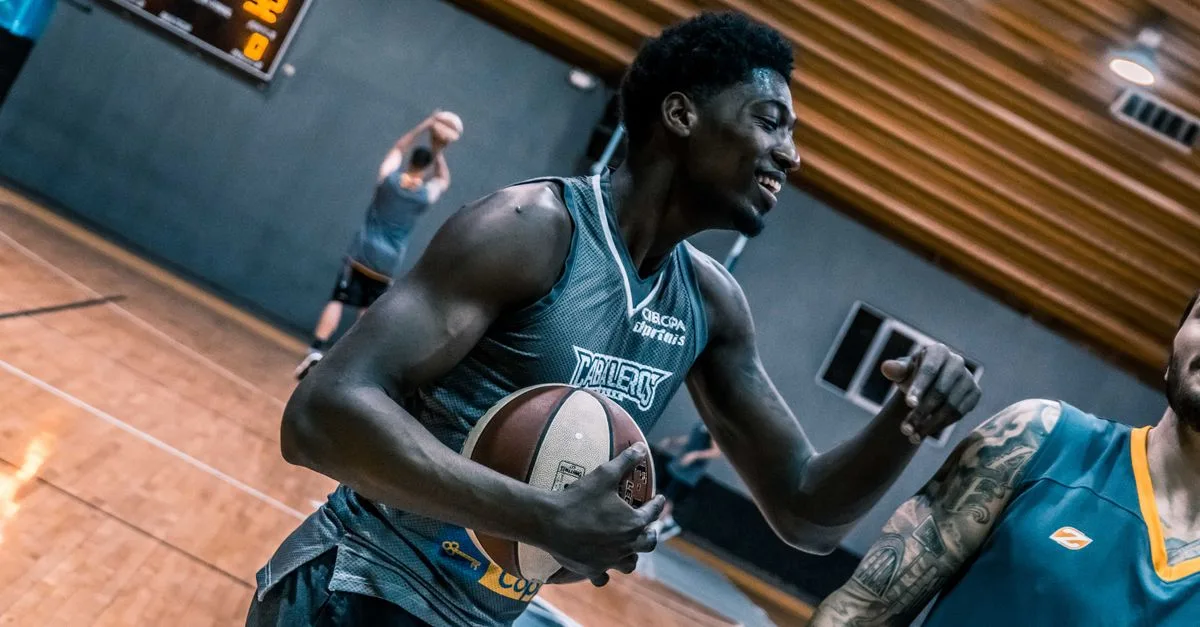 Engaging moment of basketball players during an indoor training session on a wooden court.