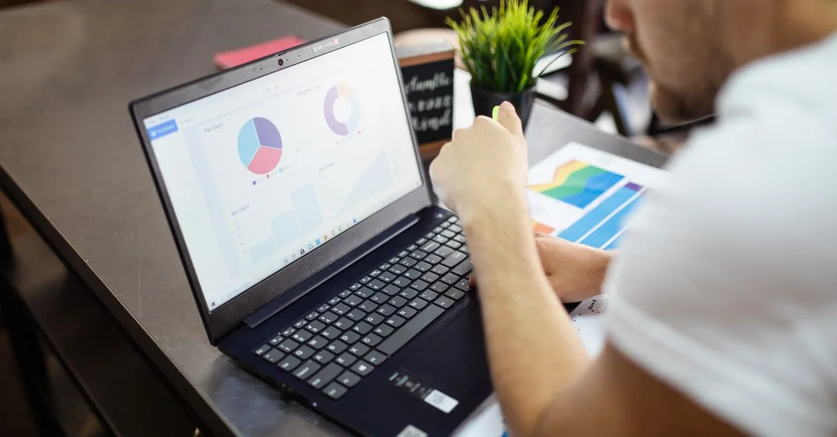 Man reviewing charts and graphs on a laptop for business analysis.