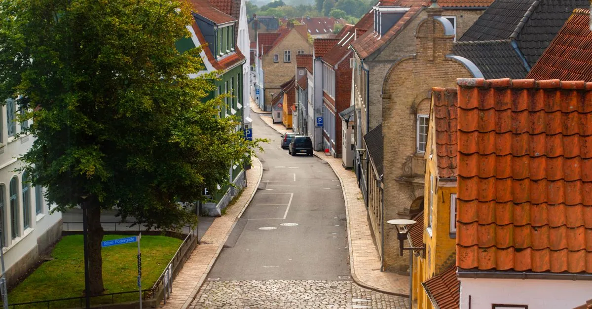 Quaint cobblestone street flanked by historic buildings in Aabenraa, Denmark.