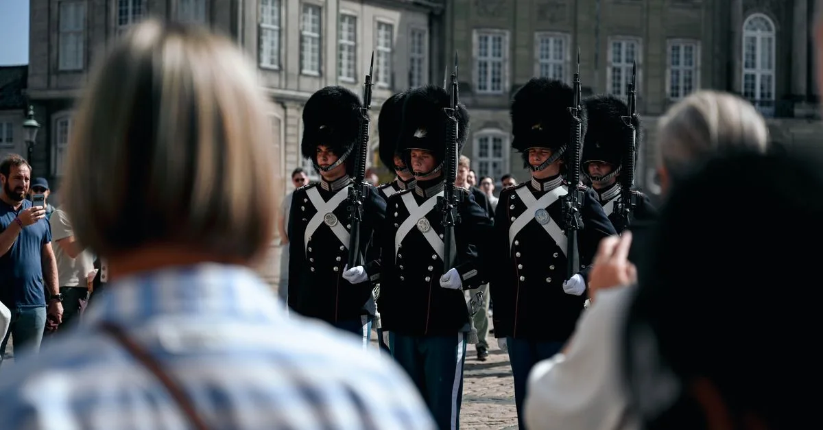 Royal guards marching at Amalienborg Palace in Copenhagen, Denmark with spectators in the foreground.