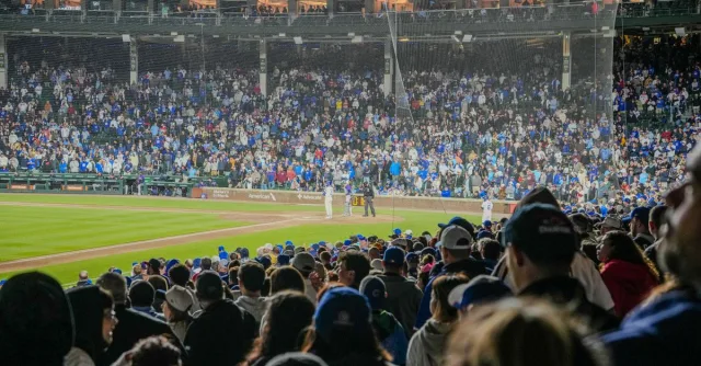 Energetic scene of a nighttime baseball game with a packed stadium crowd.