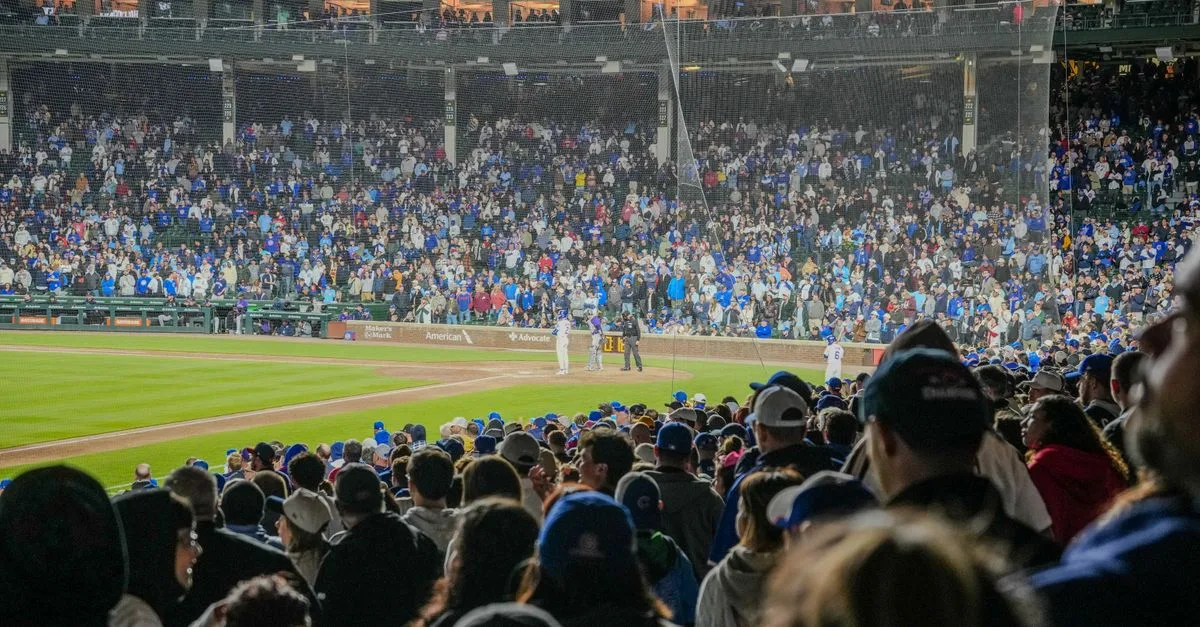Energetic scene of a nighttime baseball game with a packed stadium crowd.