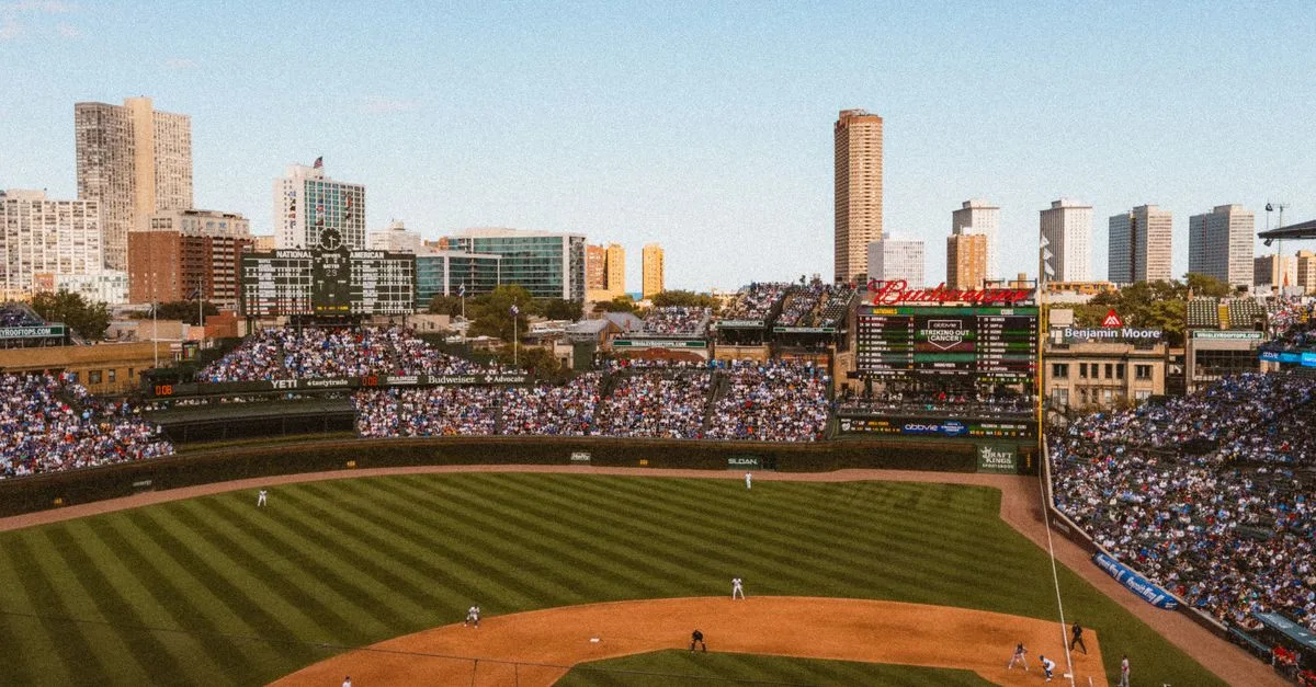 Aerial view of a lively baseball game at a famous stadium with city skyline.