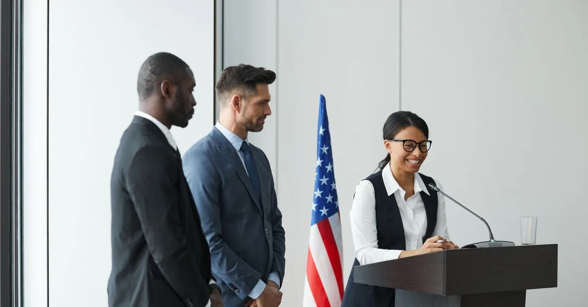 A diverse team in business attire at a podium with an American flag, showing unity and professionalism.