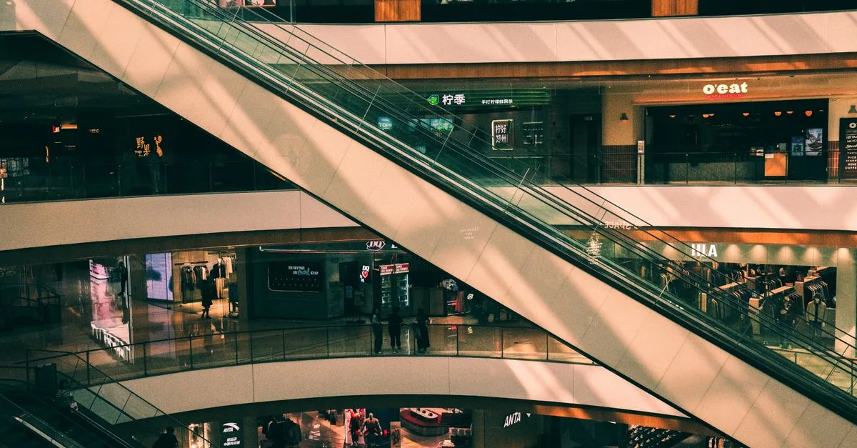 Vibrant shopping mall interior featuring escalators and retail shops across multiple levels.