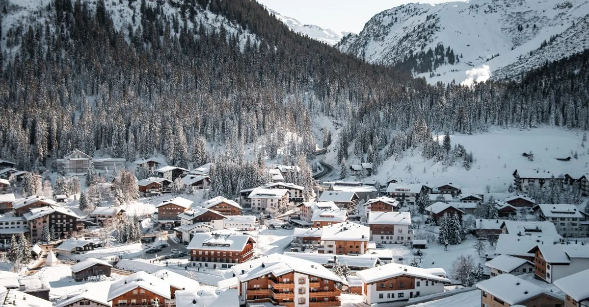 Scenic view of snow-covered village in Lech am Arlberg, Austria with mountains.