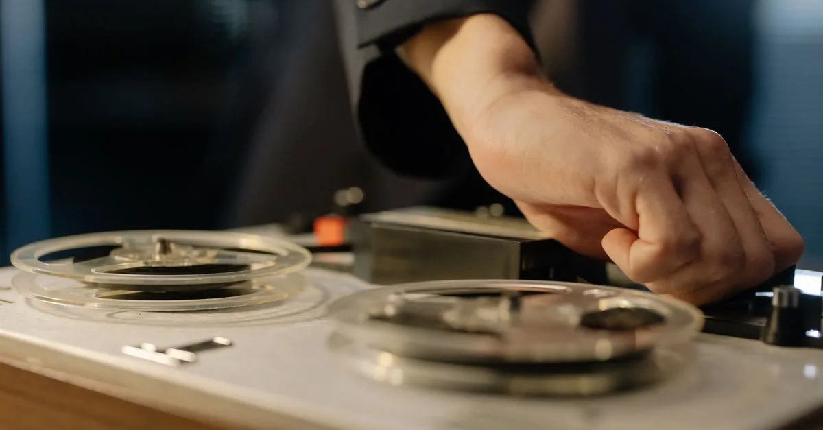 A close-up shot of a hand adjusting controls on a vintage reel-to-reel tape recorder.