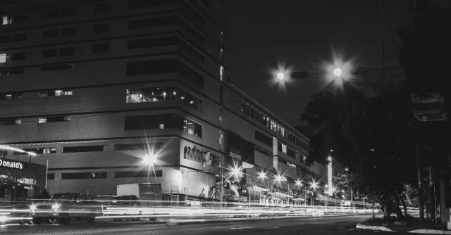 Dramatic urban night photo featuring long exposure light trails and illuminated buildings.