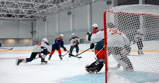 Competitive ice hockey game with players in action at an indoor rink.