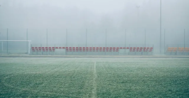 Foggy soccer field with empty bleachers, creating a serene and mysterious atmosphere.