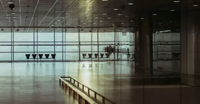 A calm and empty airport terminal in Singapore with a reflective glass facade and soft lighting.