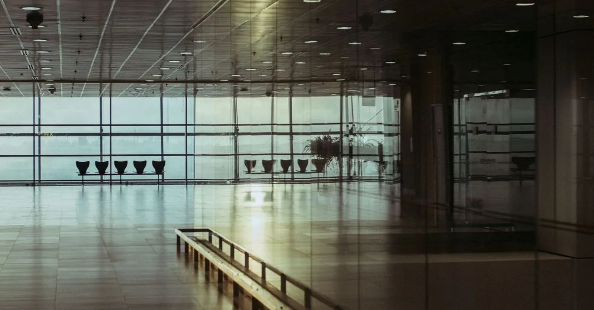 A calm and empty airport terminal in Singapore with a reflective glass facade and soft lighting.
