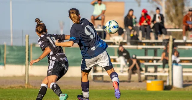 Two female soccer players in action during a competitive outdoor football match. Energetic sports scene.