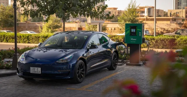 Tesla Model 3 charging at an urban electric vehicle station during daytime.