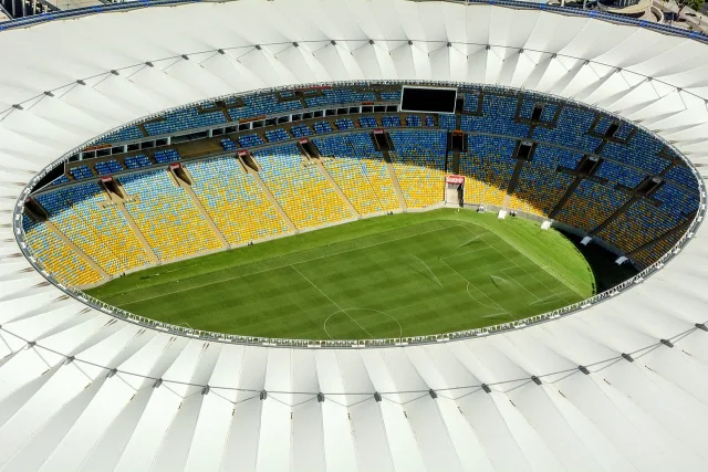 An empty football stadium pitch under stadium floodlights at night.