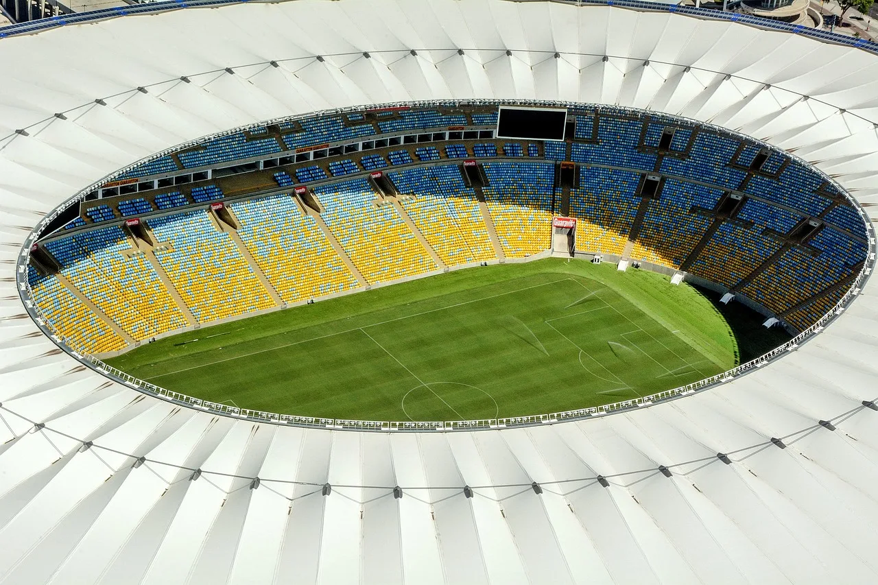 An empty football stadium pitch under stadium floodlights at night.
