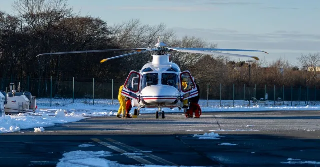 Helicopter on a snowy runway with crew preparing for flight.