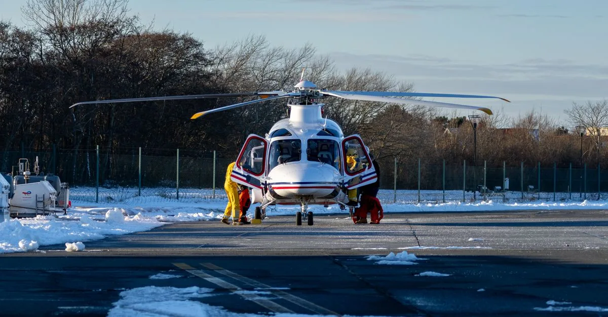 Helicopter on a snowy runway with crew preparing for flight.