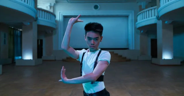 Asian male dancer performing expressive pose in an elegant ballroom ambiance.