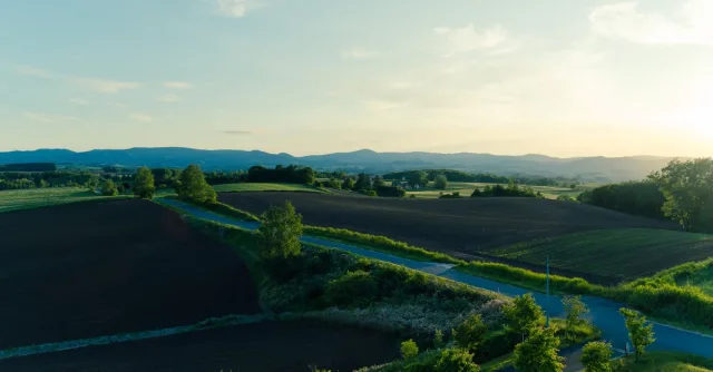 Beautiful rural landscape in Hokkaido with fields and mountains at sunset.