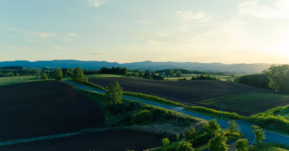 Beautiful rural landscape in Hokkaido with fields and mountains at sunset.