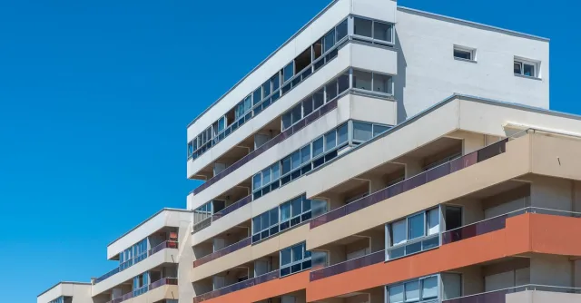 Contemporary multi-story apartment buildings with balconies under a clear blue sky, showcasing modern architecture.