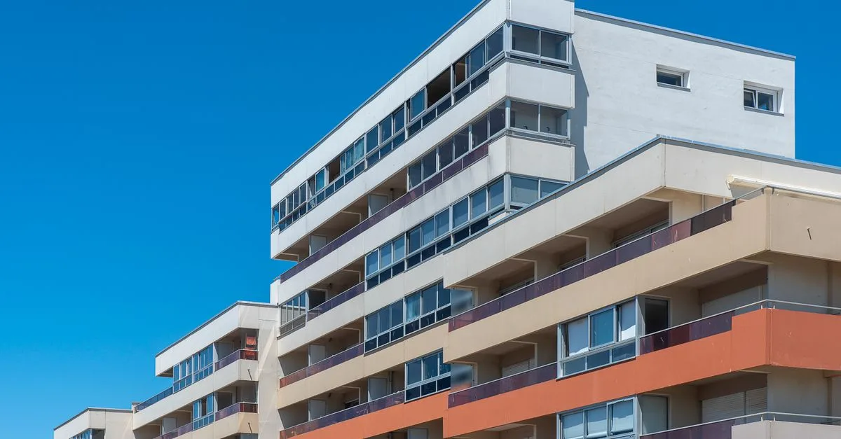 Contemporary multi-story apartment buildings with balconies under a clear blue sky, showcasing modern architecture.