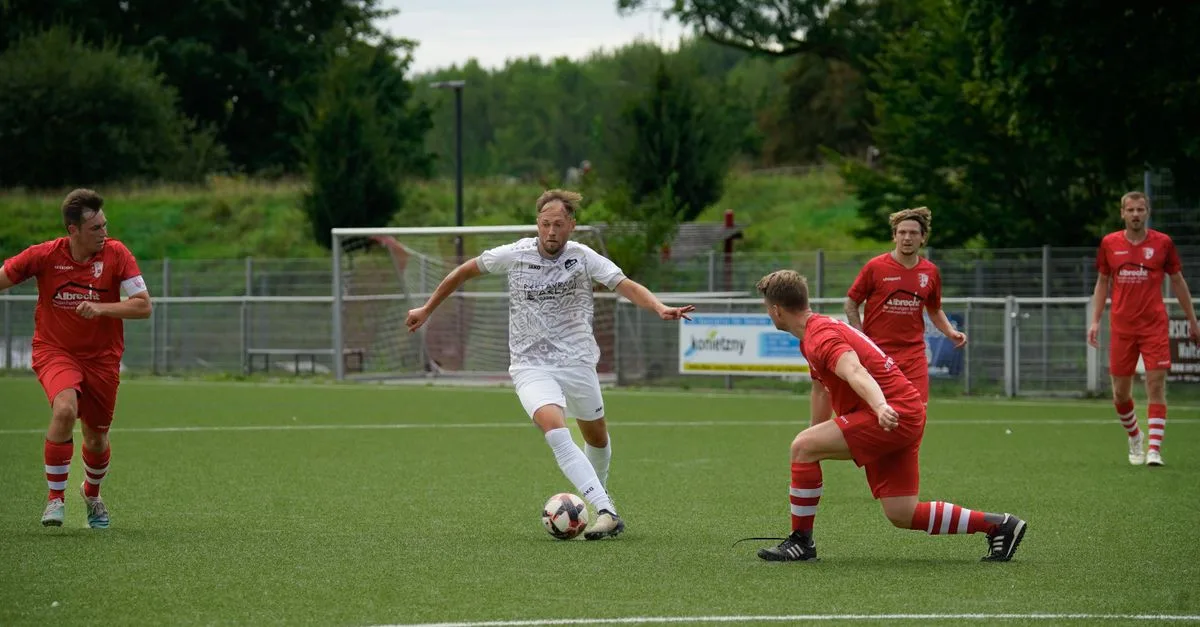 Competitive soccer players in action during a match on a green field, showcasing teamwork and athletic skill.