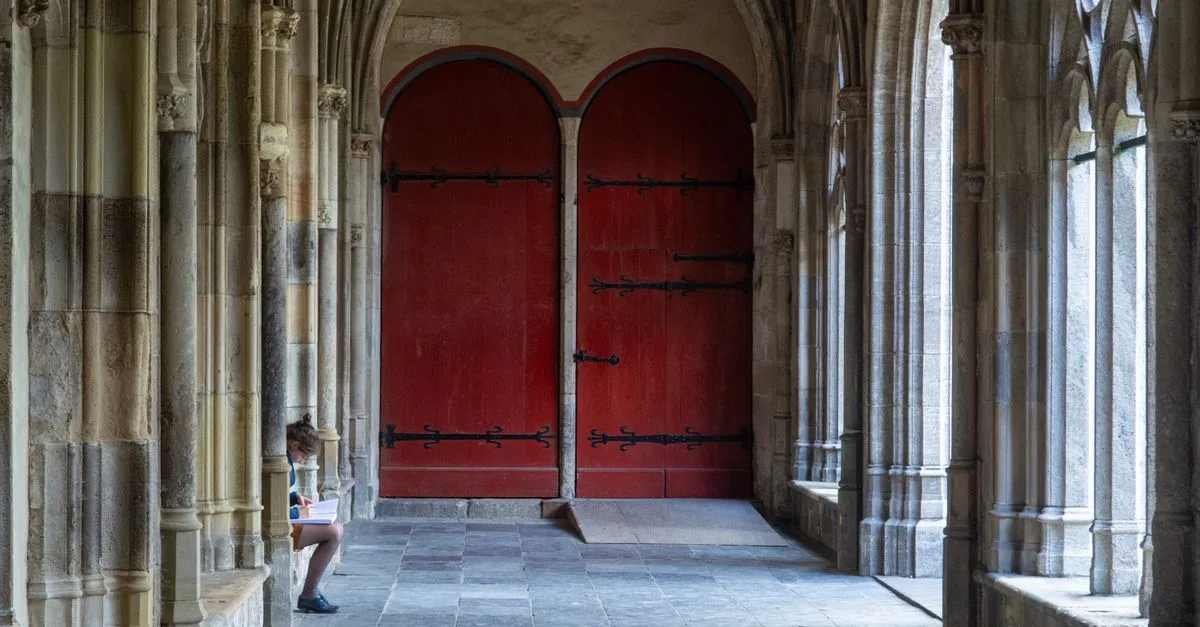 A serene Gothic cloister scene in Utrecht featuring red doors and ancient stone arches.