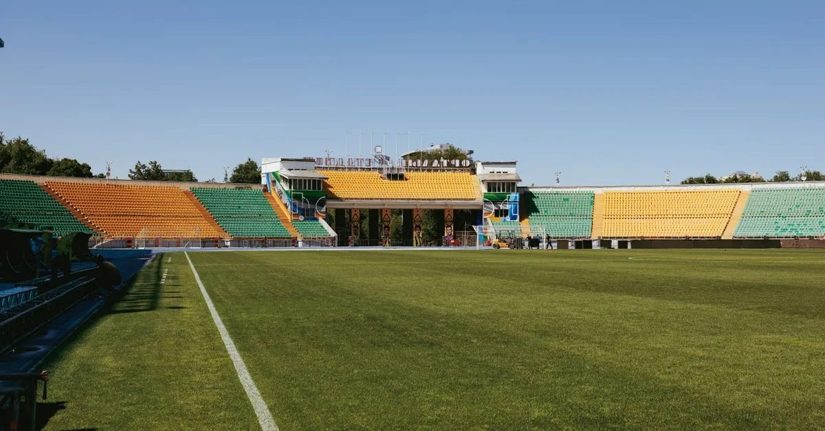 Empty football stadium with vibrant seating colors on a sunny day in Almaty, Kazakhstan.