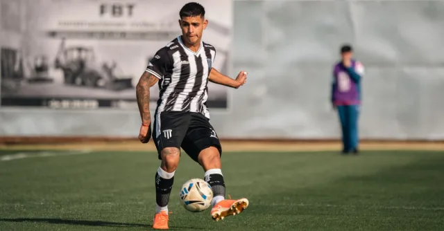 Soccer player in action kicking the ball on a sunny outdoor field.