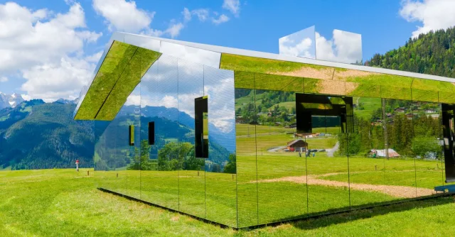 Modern mirror house reflecting Swiss Alps in Saanen, Switzerland.