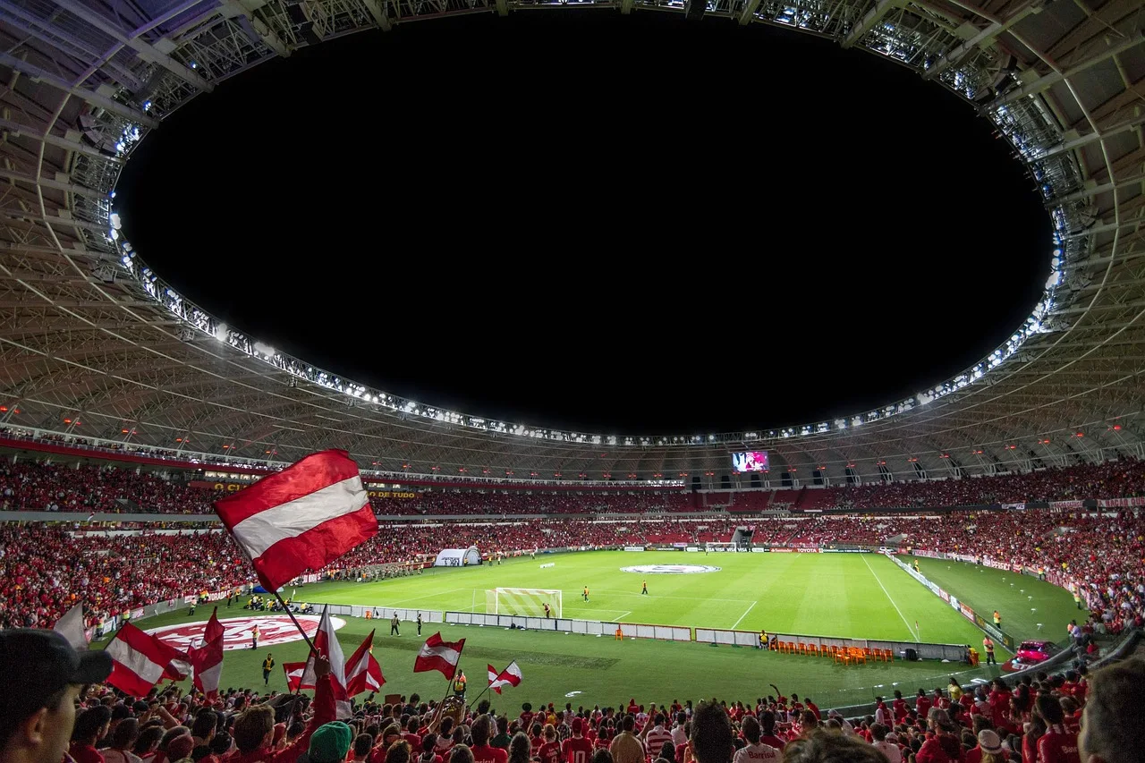 A wide view of a large, illuminated soccer stadium at night.