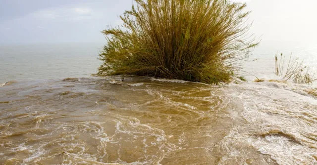 Dynamic scene with water flowing over a coastal bluff during a storm.