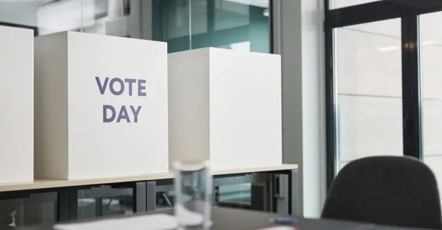 A modern office with voting booths labeled 'Vote Day' indicating election activity.