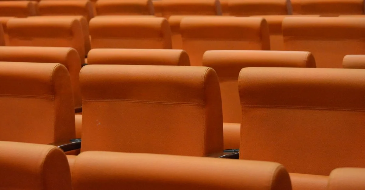 Rows of orange seats in an indoor auditorium, ideal for presentations and events.