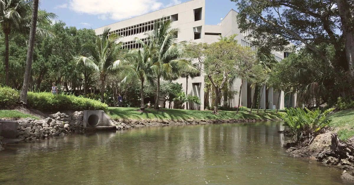 Serene view of the University of Miami campus with lush trees and a tranquil canal.