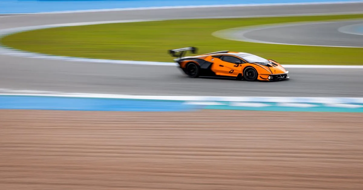 A vibrant orange sports car speeding around a race track, capturing the thrill of motorsport.