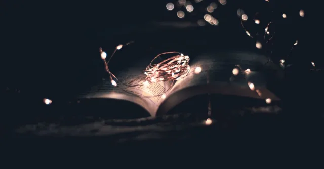 An open book beautifully illuminated by string lights, creating a magical atmosphere.