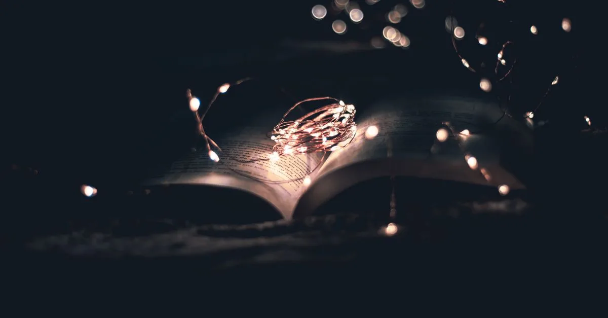 An open book beautifully illuminated by string lights, creating a magical atmosphere.