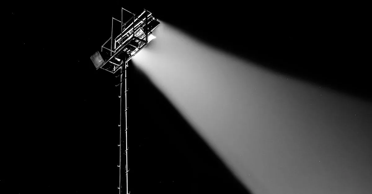 Dramatic spotlight beam shining into the night sky captured in black and white.