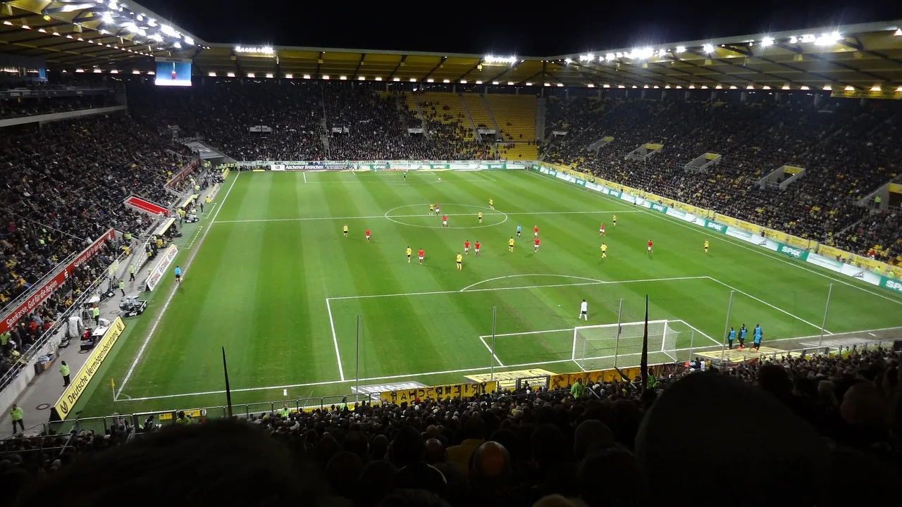 Ein beleuchtetes Fußballstadion bei Nacht mit Blick auf das Spielfeld.