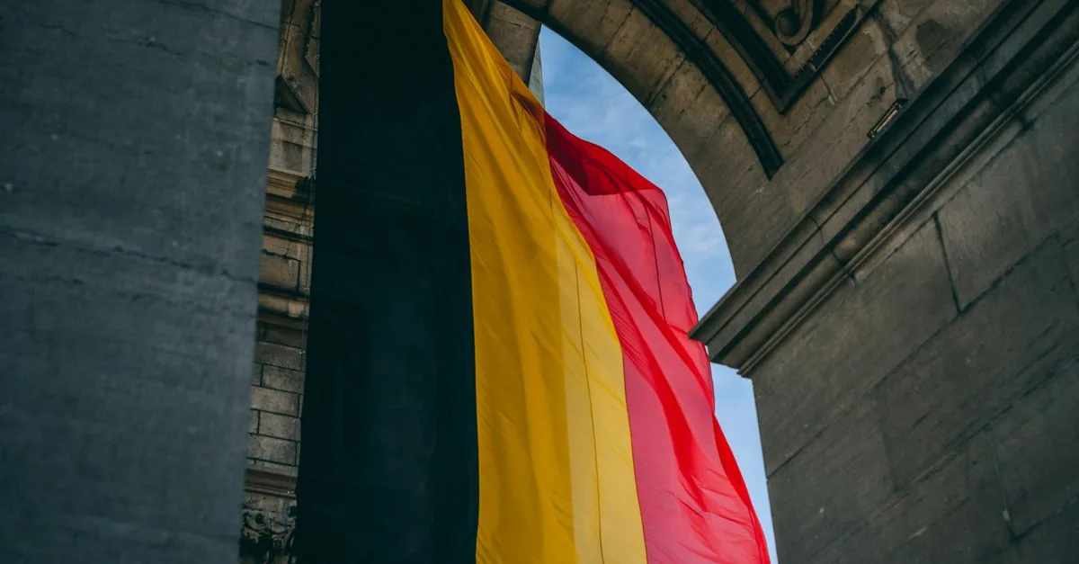 Vibrant Belgian flag under iconic archway in Brussels, symbolizing national pride.