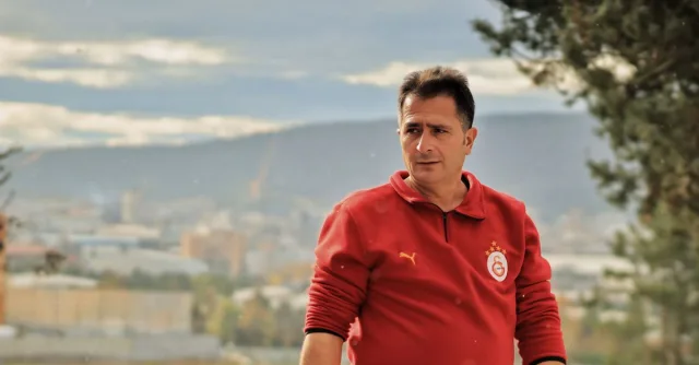 Man in red sweatshirt with city skyline in background, shot outdoors.