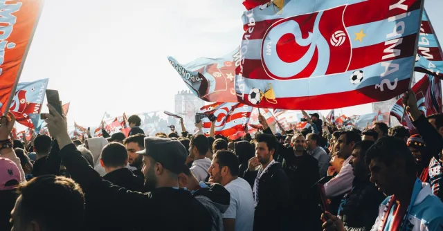 Energetic gathering with colorful flags at a lively outdoor event on a sunny day.