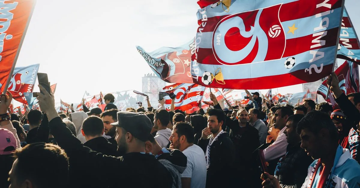Energetic gathering with colorful flags at a lively outdoor event on a sunny day.