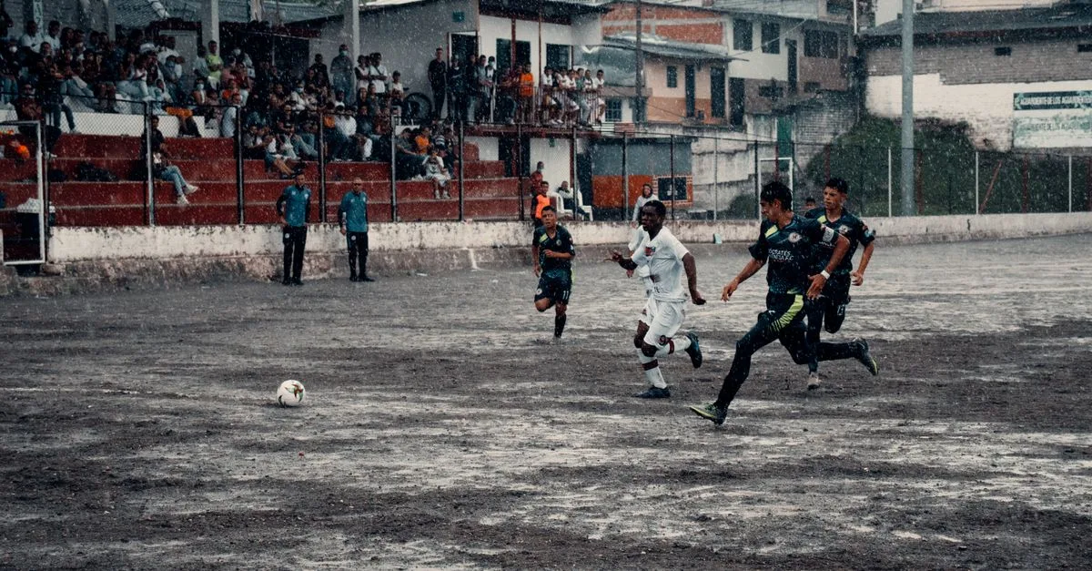 Exciting soccer game in Neira, Colombia, capturing athletes in action during a rainy match.