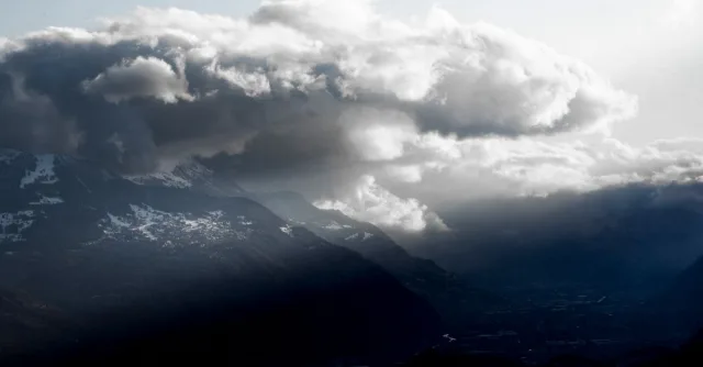 Majestic storm clouds over Crans-Montana mountains, creating a dramatic atmosphere.